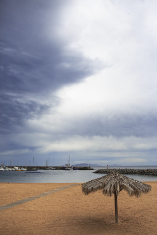 Portugal, Madeira, Machico, Yellow beach with beach umbrella, view to harbour stock photo