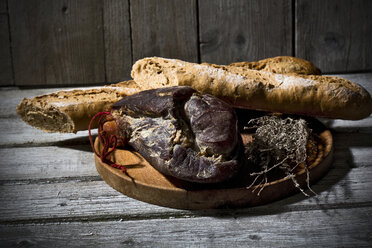 Baguette mit geräuchertem Schinken und Zwiebeln auf Holzbrett - MAEF007641