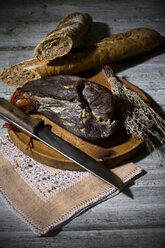 Baguette mit geräuchertem Schinken und Zwiebeln auf Holzbrett - MAEF007642