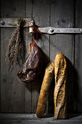 Baguette mit geräuchertem Schinken und Zwiebeln auf Holztür - MAEF007643