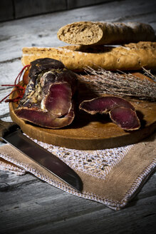 Baguette mit geräuchertem Schinken und Zwiebeln auf Holzbrett - MAEF007644