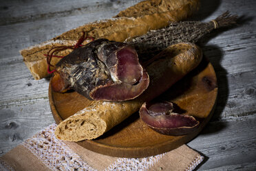 Baguette mit geräuchertem Schinken und Zwiebeln auf Holzbrett - MAEF007645