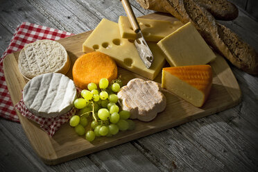 Cheese platter, different cheese, french cheddar, french soft cheese, french sheep cheese, camembert, emmentaler, and austrian mountain cheese and wholemeat baguette on wooden board - MAEF007648