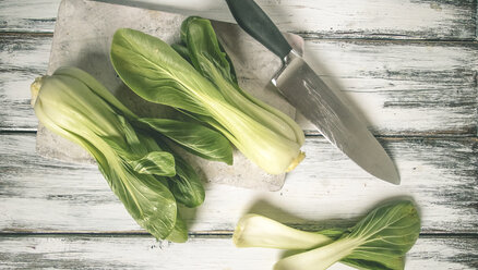 Two Pak Choi (Brassica rapa chinensis, mustard cabbage) on wooden board with knife, studio - SBDF000474