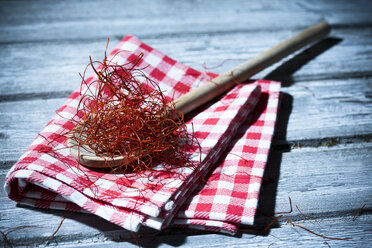 Holzlöffel mit Chilifäden auf Küchenhandtuch und Holztisch - MAEF007663