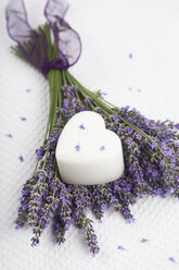 Lavendelblütenstrauß (Lavendula) und weiße herzförmige Kerze auf weißem Grund - GWF002546