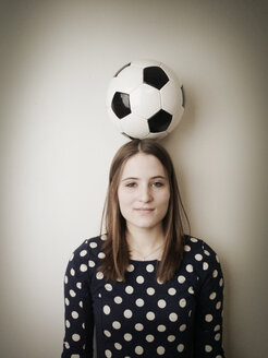 Junge Frau mit einem Fußball auf dem Kopf - JATF000594