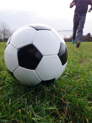 Köln, Nordrhein-Westfalen, Deutschland, Fußball im Gras liegend, junger Mann im Hintergrund - JATF000616