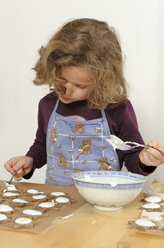 Little girl spreading cinnamon stars with sugar icing - LAF000443
