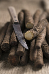 Geschnittene und ganze Schwarzwurzeln (Scorzonera hispanica) und Küchenmesser auf Jute, Nahaufnahme - MYF000120