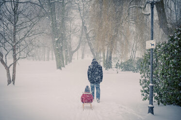 Father pulling sledge with son in snow - MJF000609