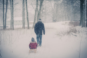 Vater zieht Schlitten mit Sohn im Schnee - MJF000698
