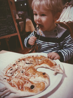 Toddler eating a dragon or fish pizza at a restaurant, Bonn, NRW, Germany - MFF000774