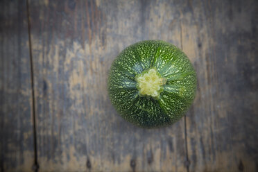 Round courgette on dark wooden table, elevated view - LVF000484