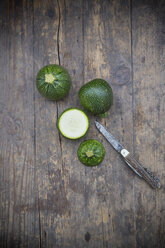 Sliced and whole round courgettes and a pocket knife on dark wooden table - LVF000479