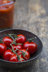 Metallschüssel mit Kirschtomaten, Einmachglas mit Tomatensauce auf Holztisch - LVF000472