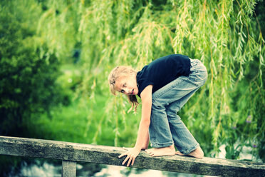 Mädchen balanciert auf dem Geländer einer Holzpromenade - PAF000270