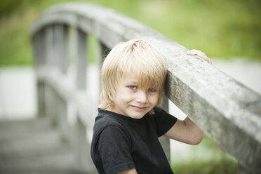 Porträt eines kleinen Jungen, der auf einer Holzpromenade steht - PAF000269