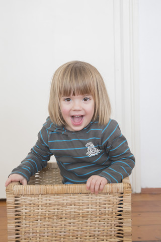 Porträt eines lächelnden kleinen Mädchens, das in einem Korb steht, lizenzfreies Stockfoto