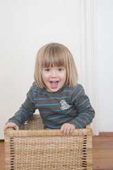 Porträt eines lächelnden kleinen Mädchens, das in einem Korb steht - LVF000495