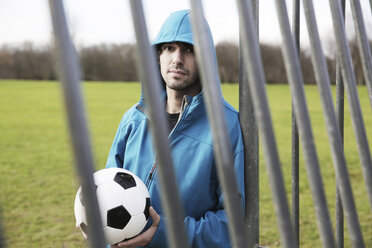 Junger Mann mit Fußball am Torpfosten lehnend - JATF000593