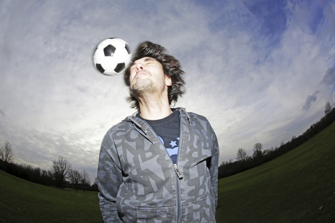 Junger Mann köpft einen Fußball, lizenzfreies Stockfoto