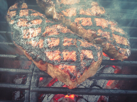 Rindersteaks auf gusseisernem Grillrost über heißem Holzkohlefeuer gegrillt - ABAF001192