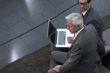 Zwei Geschäftsleute mit Laptop in einer Büro-Lobby - CHAF000040