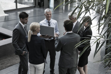 Gruppe von Geschäftsleuten mit Laptop im Gespräch in der Lobby - CHAF000035