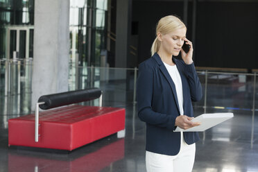 Businesswoman on cell phone in office lobby - CHAF000017