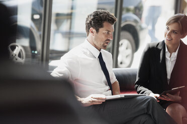 Businessman and businesswoman talking in office lobby - CHAF000016