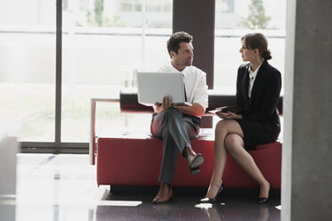 Businessman and businesswoman talking in office lobby - CHAF000032