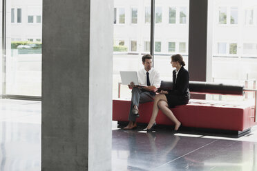 Businessman and businesswoman talking in office lobby - CHAF000031