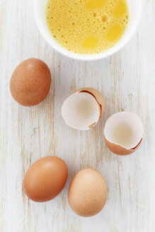 Schale mit aufgeschlagenen Eiern und Eierschalen auf Holztisch - EVGF000336