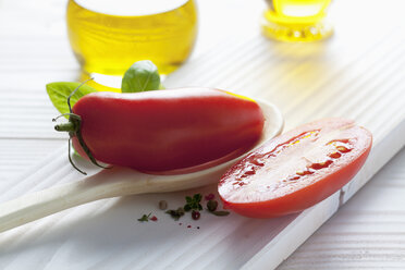 San Marzano tomato on wooden spoon, olive oil, basil and peppercorns on wooden table - CSF020678