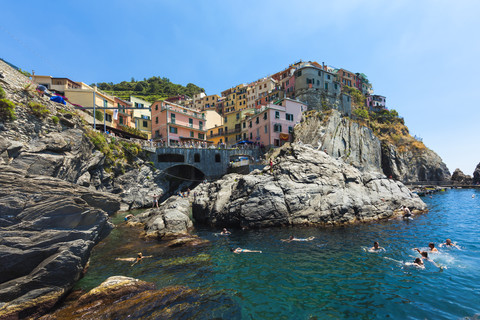 Italien, Ligurien, La Spezia, Cinque Terre, Manarola, Blick auf das Dorf, badende Menschen im Vordergrund, lizenzfreies Stockfoto
