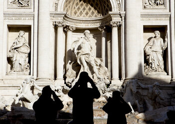 Italien, Rom, Blick auf den Trevi-Brunnen mit Silhouetten von drei Touristen davor - DIS000452