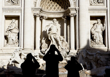 Italy, Rome, view to Trevi Fountain with silhouettes of three tourist in front - DIS000452