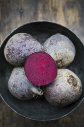 Bowl of whole beetroots and a half on wooden table - LVF000503