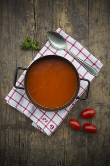 Kochtopf mit Tomatensuppe auf Küchenhandtuch und Holztisch - LVF000507