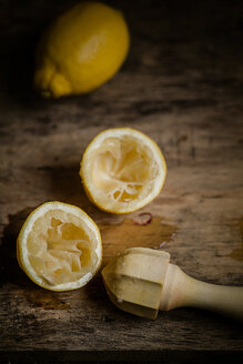 Halbe ausgepresste Zitrone, Zitrone und hölzerne Zitronenpresse auf Holztisch - SBDF000505