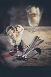 Zwei Gläser Vanilleeis mit Schokoladengranulat, Löffel und Küchenhandtuch auf Holz - SBDF000511