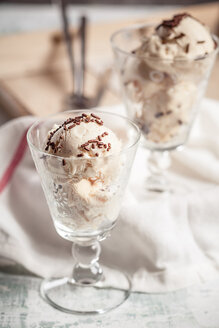 Zwei Gläser Vanilleeis mit Schokoladengranulat und Küchentuch auf Holz - SBDF000512