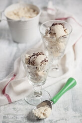 Two glasses and of vanilla icecream with chocolate granules, ice cream scoop and kitchen towel on wood - SBDF000515