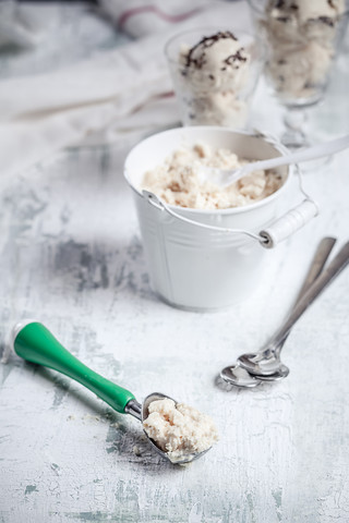 Zinkeimer mit Vanilleeis, Eisportionierer und Löffel auf Holz, lizenzfreies Stockfoto