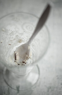 Glas mit Resten von Vanilleeis mit Schokoladengranulat und einem Löffel - SBDF000517