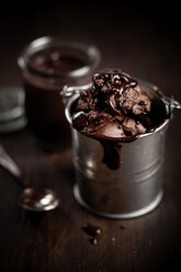 Metal bucket of chocolate icecream and chocolate sauce on wood - SBDF000518