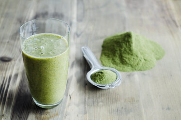 Moringa-Pulver auf Löffel und Holztisch und ein Glas Moringa-Smoothie - CZF000133