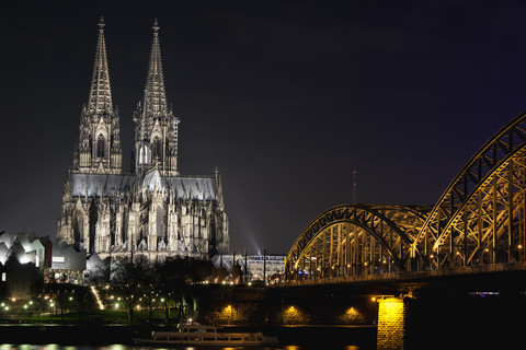 Germany, North Rhine-Westphalia, Cologne, Cologne Cathedral and Hohenhollern Bridge over the Rhine river by night stock photo