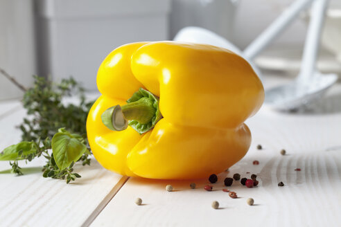 Gelbe Paprika (Capsicum), Gewürzmischung und Pfefferkörner auf weißem Holztisch - CSF020805